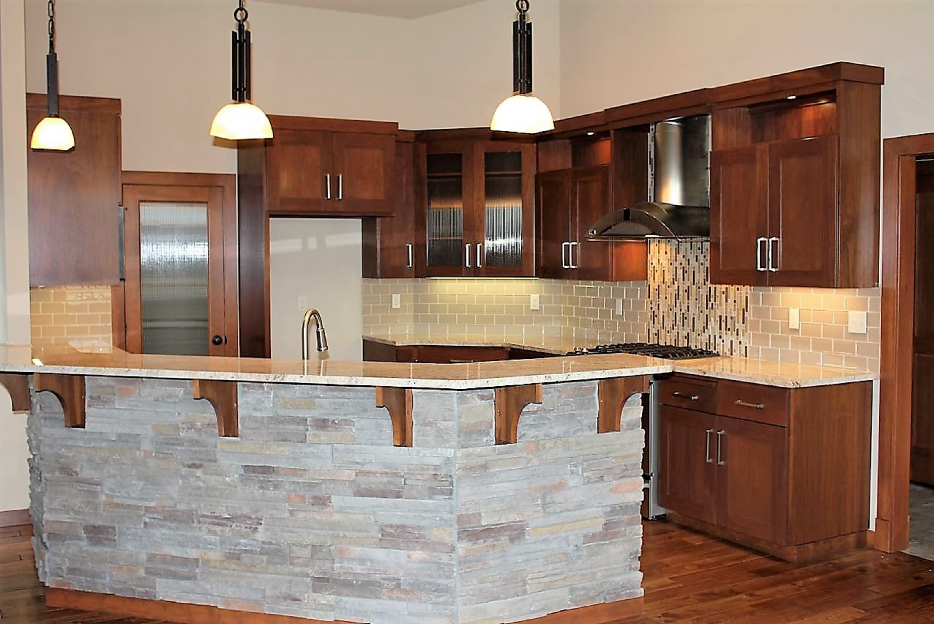 Kitchen  contemporary style  walnut  dark color  recessed panel  full overlay  rock island back   4 bar supports  reeded glass doors  chimney style hood with top  open space at top of the uppers