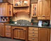Thumb kitchen  traditional style  hard maple  medium color  raised panel  distressed  half arch doors  hood above sink  glass grid doors with seeded glass  posts   arch at sink front  cubbies  small drawers at bottom