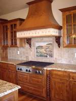 Thumb kitchen  traditional style  knotty alder  medium color  raised panel with arch  curved wood hood  turned posts   legs by rangetop  glass grid doors  standarad overlay